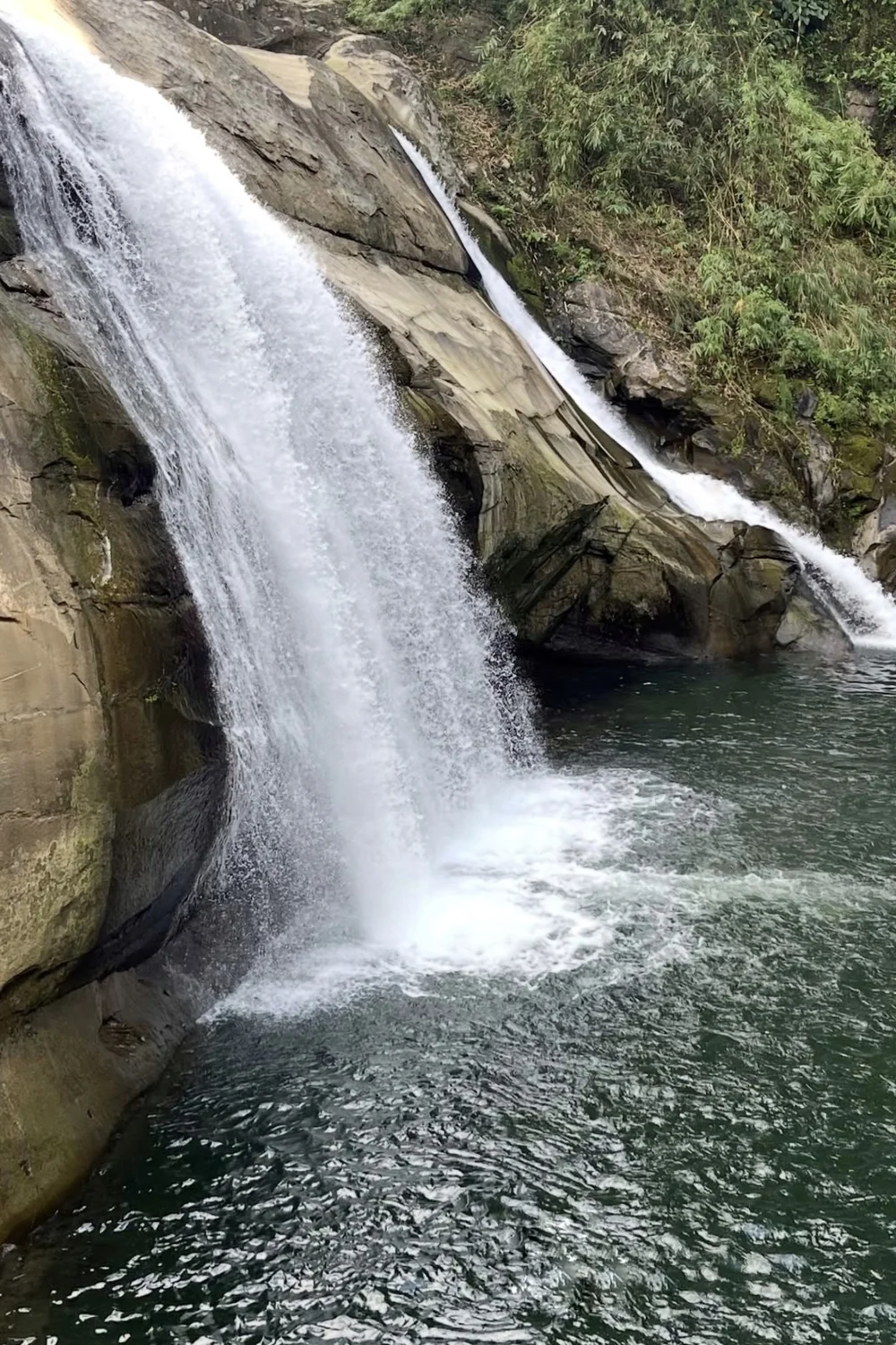 Water cascades over rock into the forest-lined pool at Tangadan Falls