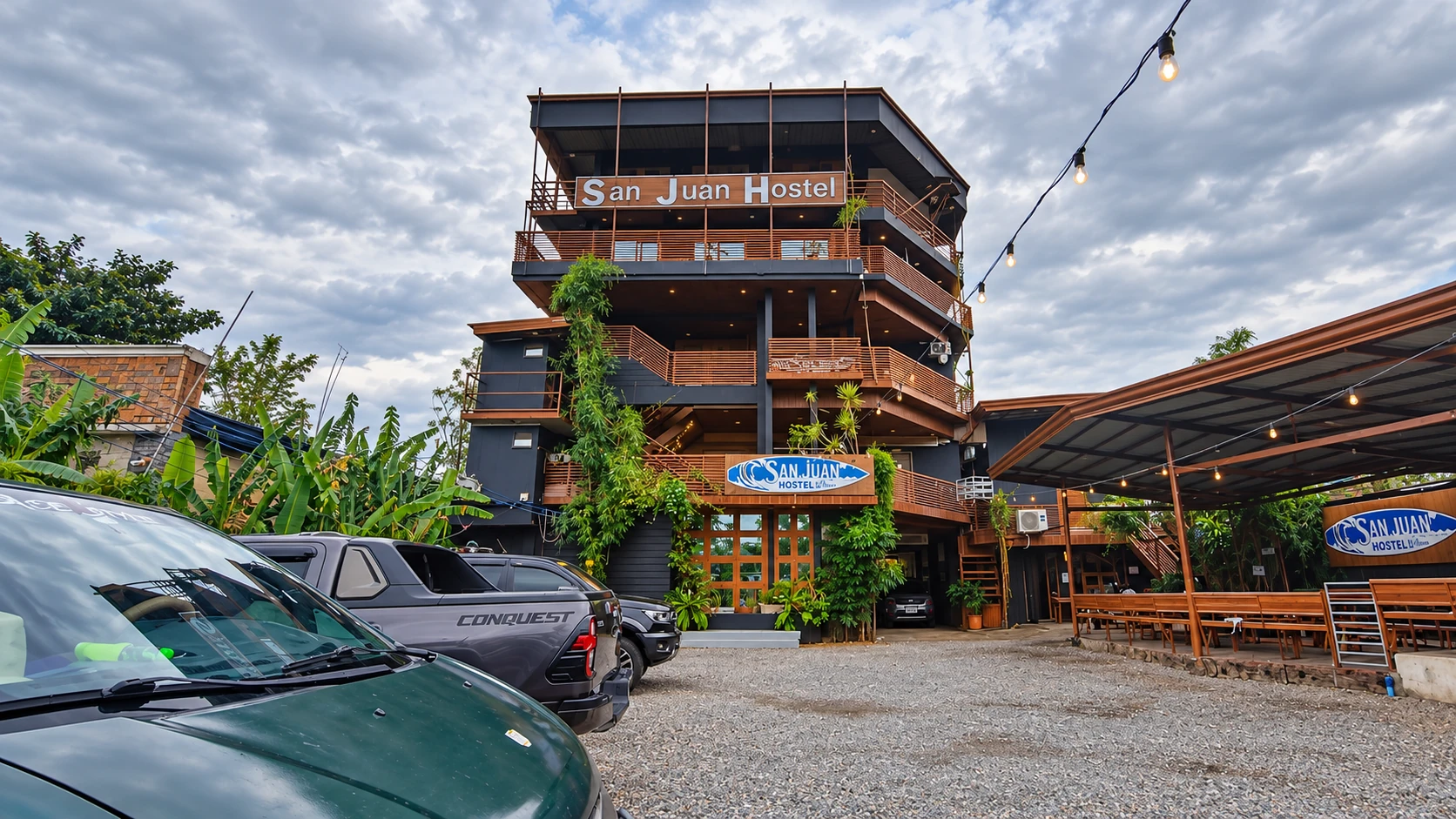 The San Juan Hostel exterior with timber balconies, tropical plants, and welcoming signage